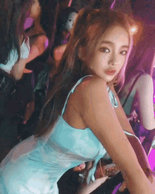 a woman in a blue dress is standing in a crowd of people in a club .