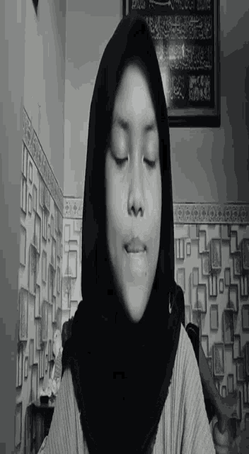 a black and white photo of a woman wearing a hijab and smiling .