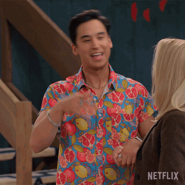a man in a colorful shirt is standing next to a woman with a netflix logo on the bottom