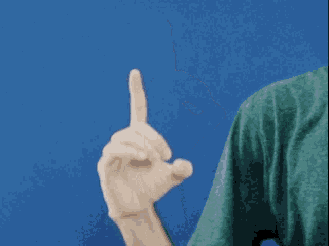 a man in a green shirt is making an ok sign with his fingers