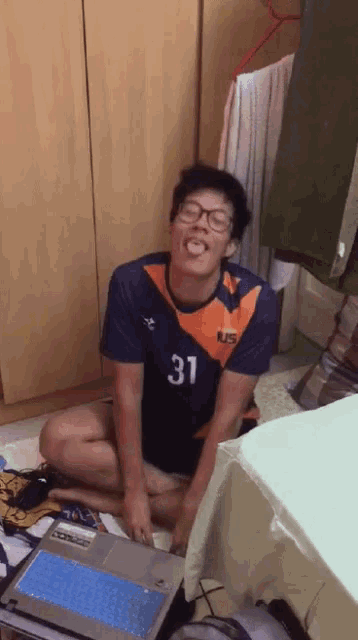 a man wearing a blue and orange shirt with the number 31 sticking his tongue out