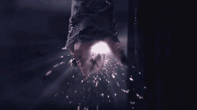 a close up of a person 's fist with sparks coming out of it in a dark room .