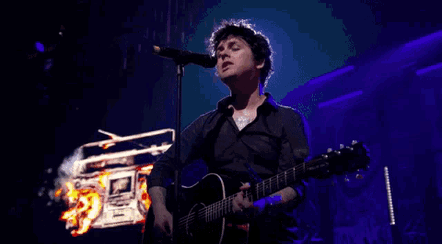 a man is singing into a microphone while holding a guitar