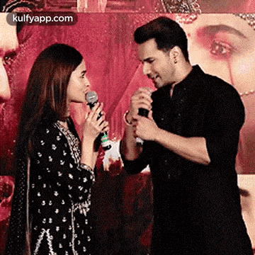 a man is holding a microphone and talking to a woman .
