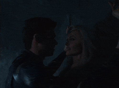 a man in a black suit stands in a dark room