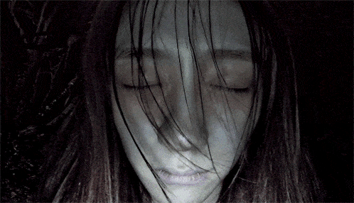 a woman with long hair and black eyes looks scary