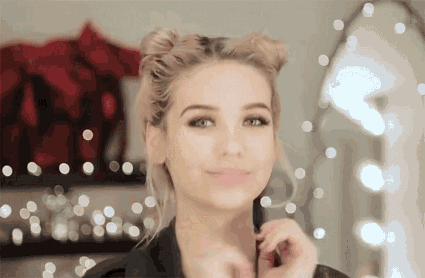 a woman with blonde hair is standing in front of a mirror and smiling .