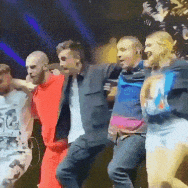 a group of people are dancing on a stage and one of them is wearing a shirt that says ' i love you '