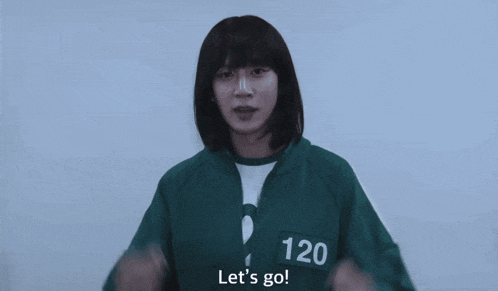 a girl wearing a green jacket with the number 12 on it is waving her hands and saying let 's go .