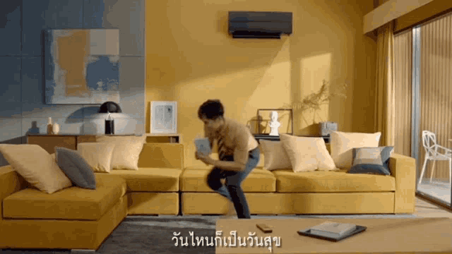 a man is jumping on a yellow couch in a living room with asian writing on the wall