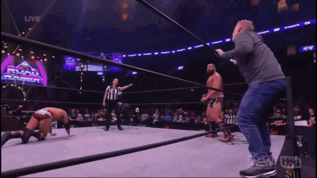 a man is standing in a wrestling ring with a referee in the background