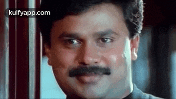 a man with a mustache is looking at the camera .