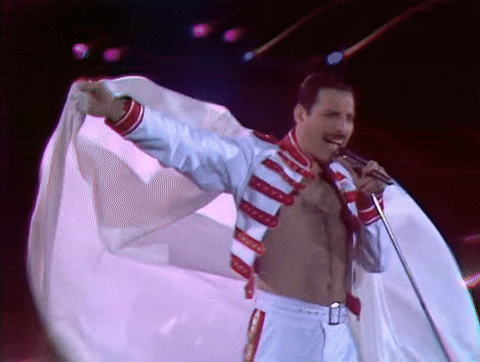 a shirtless man is singing into a microphone on a stage while holding a white cloth .