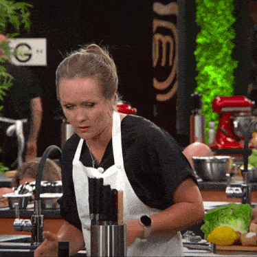 a woman in an apron stands in front of a sign that says ' g ' on it