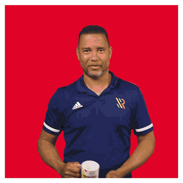 a man wearing a blue adidas shirt holds a mug