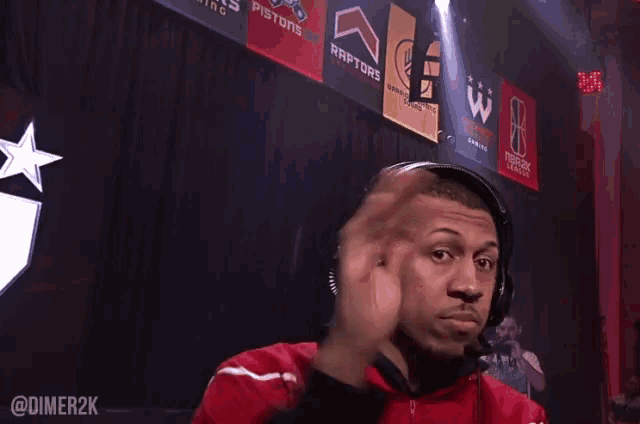 a man wearing headphones stands in front of a sign that says raptors on it