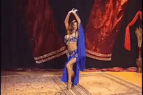 a belly dancer is dancing on a rug on a stage in a room .