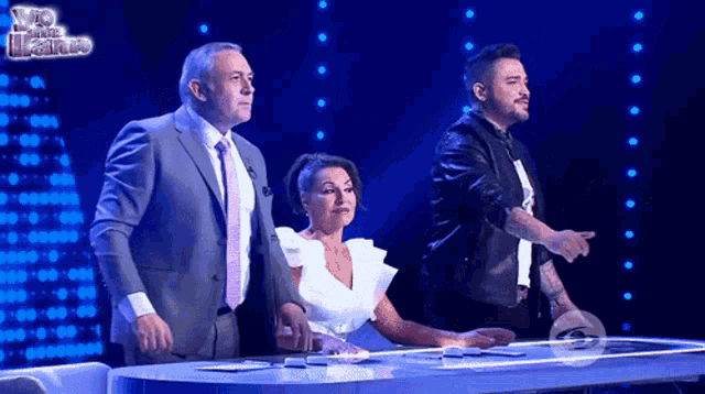 a man in a suit and tie is standing next to a woman and a man in a leather jacket