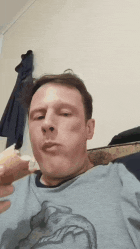 a man wearing a blue shirt with a dolphin on it is eating something