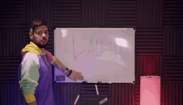 a man standing in front of a white board that says laugh