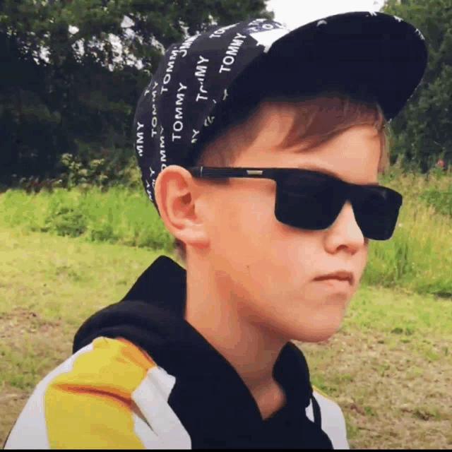 a young boy wearing a tommy hat and sunglasses