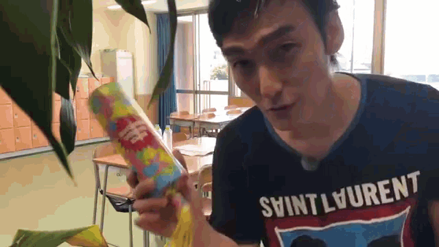 a man wearing a saint laurent shirt holds a can