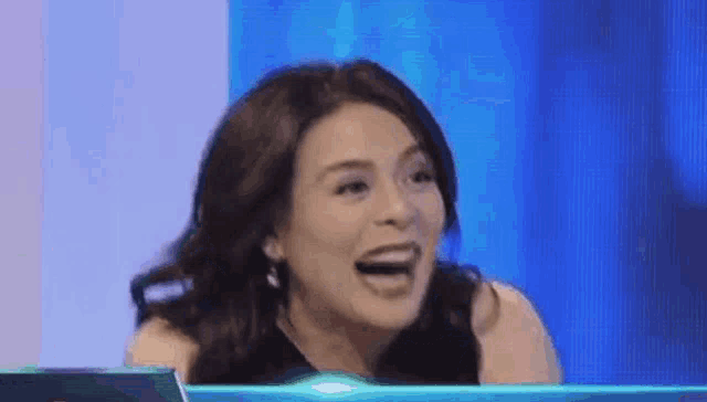 a woman is laughing while sitting in front of a blue screen .