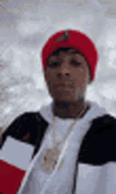 a man wearing a red beanie and a black and white jacket .