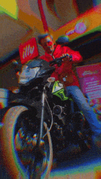 a man sits on a motorcycle in front of a sign for illy