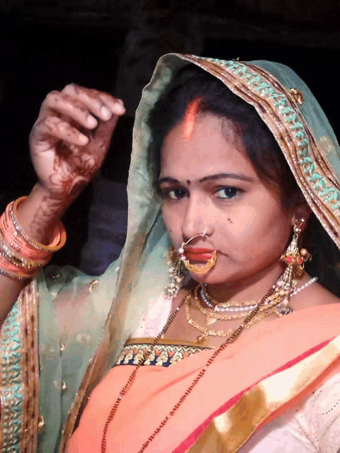 a woman with a nose ring is wearing a veil and bracelets