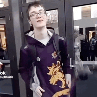 a young man wearing a purple hoodie with a wolf on it is standing in front of a door .