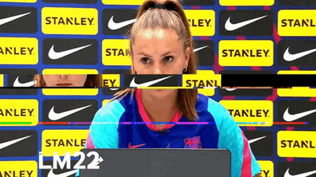 a woman is sitting in front of a wall that has nike logos on it