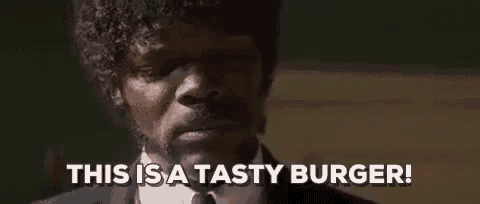 a man in a suit and tie is making a funny face and saying `` this is a tasty burger ! ''