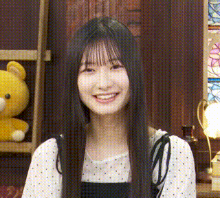 a young woman with long black hair is smiling in front of a yellow teddy bear .