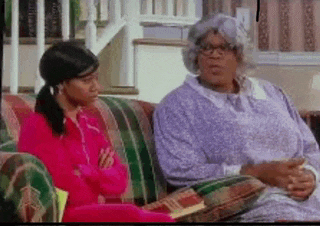 two women are sitting on a couch with their arms crossed .