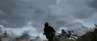 a man in a gas mask stands in a field with a rifle