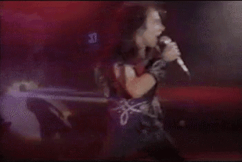 a man in a purple shirt is standing on a stage in front of a crowd .