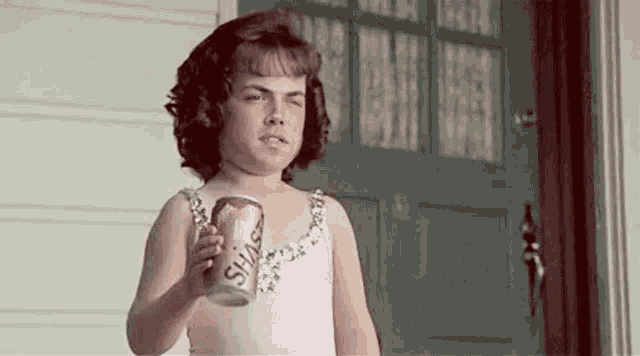a little girl is holding a can of soda in her hand .