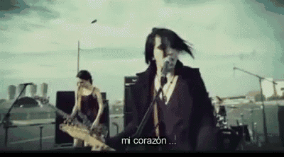 a man is singing into a microphone while a woman plays a guitar in the background .