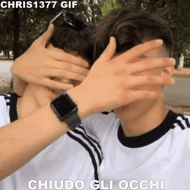 a man wearing an apple watch is covering another man 's eyes with his hands