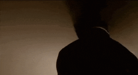 a silhouette of a man in a hooded jacket is standing in the dark .