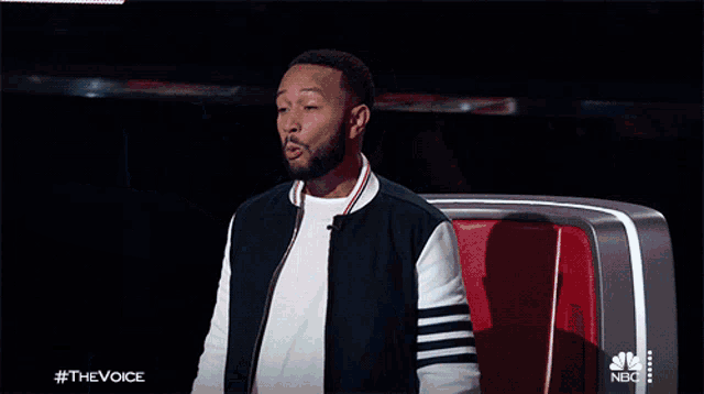 a man is sitting in a chair with his arms outstretched and a nbc logo in the background