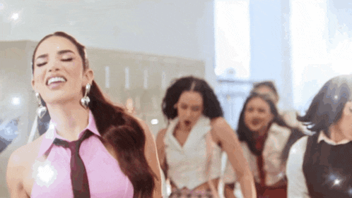 a woman in a pink top and tie is dancing with a group of women .