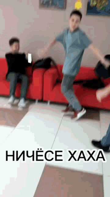 a man is jumping in the air while another man sits on a red couch behind him .