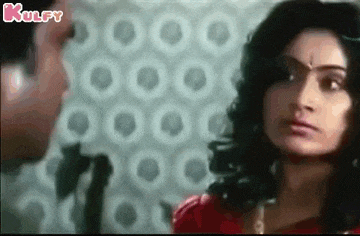 a woman in a red dress is looking at a man in a room .