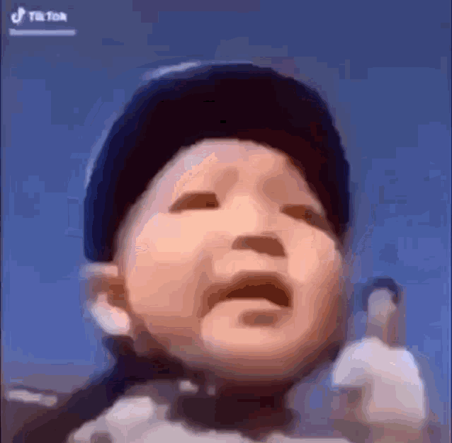 a baby is crying and wearing a black hat .