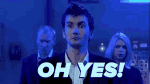 a man in a suit is standing in front of a group of people with the words oh yes written on the screen .