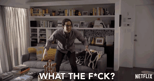a man is jumping on a couch with the words " what the f * ck " written below him