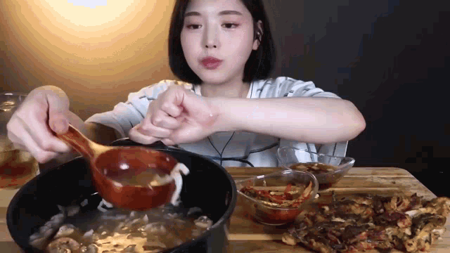 a woman is holding a wooden ladle over a pot of food .