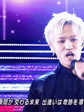 a man singing into a microphone with chinese writing on the bottom right